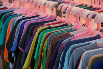 Huge selection of different used clothes for men, women and children on the rack in a second hand shop or thrift store. Concept of waste problem in fashion industry.