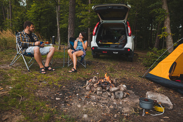 Wall Mural - couple sitting in portable chairs drinking tea talking. camping summer activities