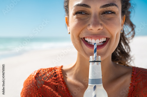 Photographie Young happy woman drinking soft drink on beach