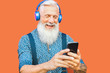 © Alessandro Biascioli - Senior man using mobile smartphone while listening music playlist with wireless headphones - Mature hipster male having fun with technology outdoor - Elderly people lifestyle and tech concept
