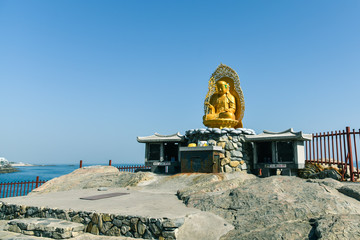 Busan city, South Korea - NOV 01, 2019: Chinese culture golden Buddha sculpture that standing on the respective shrine near Haedong Yonggung Temple.