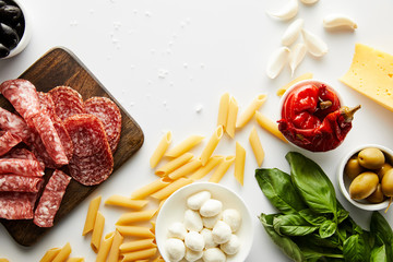 Wall Mural - Top view of pasta, meat platter, basil leaves and ingredients on white background