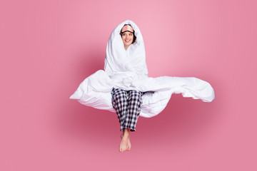 Wall Mural - Full size photo of cheerful lady late morning sit bed hold around head warm blanket look empty space wear mask white plaid pajama pants barefoot isolated pink color background