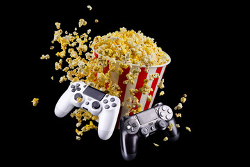 Canvas Print - Flying popcorn and video game joystick gamepad isolated on a black