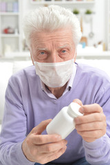 Sticker - Portrait of sad sick senior man with facial mask holding pills