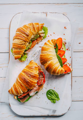 Poster - The concept of a hearty and tasty breakfast of fresh classic croissants with a variety of toppings from ricotta jamon avocado, strawberries, sun-dried tomatoes, and French mustard.