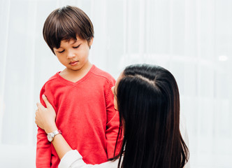 asian happy parent beautiful mother mom getting dressed clothes on her kid boy son at home befor goi