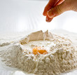 Adding salt to the heap of flour with egg for cooking
