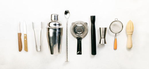 Steel bar tools and accessories for making cocktail. Shaker, jigger, strainer, spoon, tongs, muddler. Alcohol drink and beverages preparation concept. White background, top view, copy space