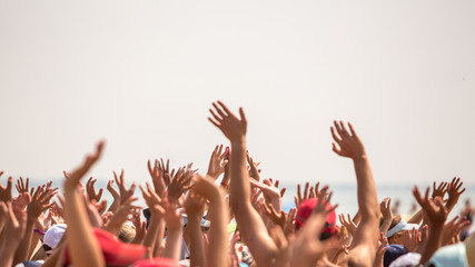 group of happy young people with hands up to the sky