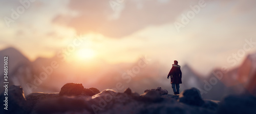 Fotomural Man on the peak of mountain looking at sunset sky