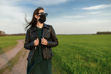 A girl in a medical mask runs or walks on a green field. Quarantine spring summer. coronavirus. COVID 19. Flu virus, colds