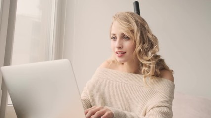 Canvas Print - Young gorgeous positive smiling blonde woman indoors at home using laptop computer