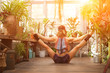 © Nelly - A young woman practices yoga among the urban jungle. Girl in yoga asanas and Pilates at home close-up and copy space.
