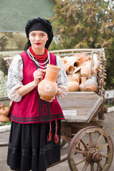 Beautiful girl in national dress. Holding an ancient pot in his hands. Antique clothing of the late 19th century. Beautiful dress and skirt on a woman. The concept of rural life, national traditions