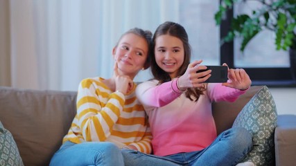 Canvas Print - people, technology and friendship concept - happy teenage girls taking selfie with smartphone sitting on sofa at home