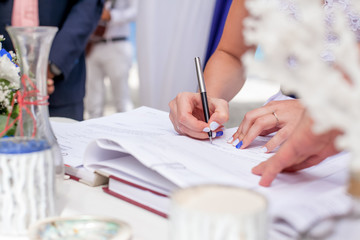 bride signing wedding marriage certificate with pen on outdoor wedding ceremony