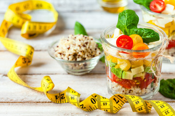 Wall Mural - Concept of healthy food, clean eating, low calories delicious meal. Salad with quinoa and fresh vegetables with olive oil in glass jar. Tape measure, zero waste no plastic. Close up wooden background