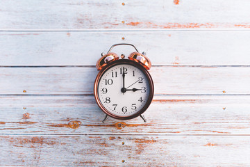 Retro vintage alarm clock on wooden background. Orange and teal style. Time concept. Isolated.