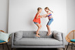 © Lisa Tichané - Two happy little girls jumping on couch at home