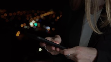 Close up woman hands using mobile phone on beautiful night city lights bokeh background. Young stylish people lifestyle with smart phone. Browsing website, scrolling