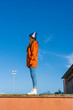 © Westend61 - Teenage girl standing on wall against sky listening music with headphones