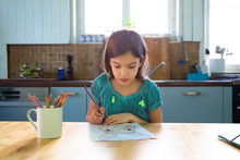 Little Girl Sitting At Kitchen Table, Drawing An Easter Bunny