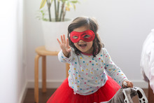 Portrait Of Little Girl Wearing Red Mask And Tulle Skirt At Home Having Fun