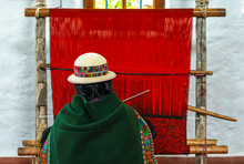 A Senior Indigenous Bolivian Aymara Woman In Traditional Clothing Doing A Demonstration Of Fabric Or Textile Weaving In Sucre, Bolivia.