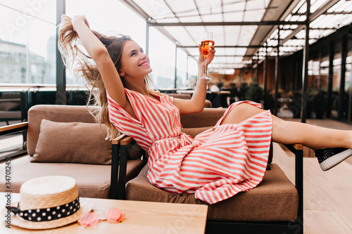 Fotomural Ecstatic blonde girl playing with her hair while chilling in cafe