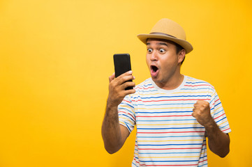 Asian man happy with his smartphone on yellow background. young man using looking at smartphone.