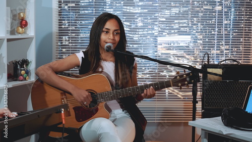 Fotografía Black woman vocalist recording a song and playing guitar in home studio
