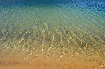 Clear blue water with light waves and beautiful sun glare. Natural background.