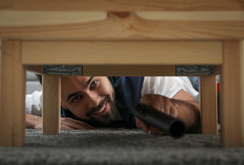 Wall Mural - Young man using vacuum cleaner at home