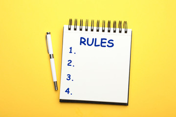 Wall Mural - Notebook with list of rules and pen on yellow background, flat lay