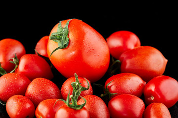 Big tomato and small grape cherry tomatoes on a black background. Low calorie food