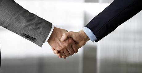 Business people in office suits standing and shaking hands, close-up. Business communication concept. Handshake and marketing