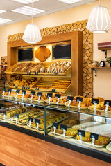 Wall Mural - Baked baguettes and pies on showcase in bakery shop. Inscriptions in russian with the name baking: cheesecake, bun, pie, baguette and others. 30 percent discount offer