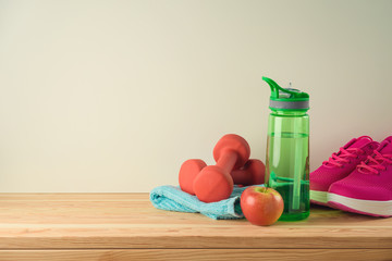 Wall Mural - Fitness and healthy lifestyle background with bottle of water, dumbbells and sport shoes on wooden table