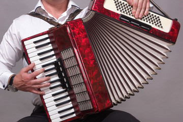 Closeup detail of hands playing a red accordion instrument