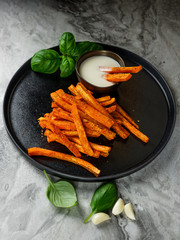 Wall Mural - Homemade diet snack - fried carrot sticks with white sauce on table background.