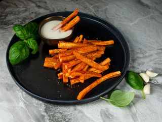 Wall Mural - Homemade diet snack - fried carrot sticks with white sauce on table background.