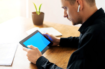 Close-up portrait of young man in smart casual shirt is using laptop for work. Male hands on keyboard. Freelancer, developer