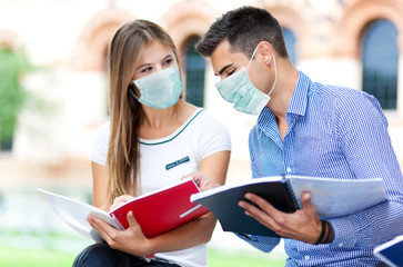 Couple of students talking together wearing a mask - coronavirus concept