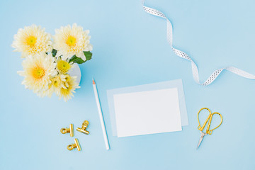 Wall Mural - mockup white wedding invitation and envelope with flowers in a vase on a blue background