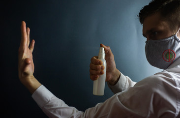 A man in a protective mask against coronavirus sprays an antiseptic on his hands, COVID-19
