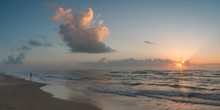 Panoramic View Of Sunset Over Calm Ocean Waves With Lone Woman Standing On The Shore