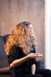 © Vagengeim - Blonde girl with volume shiny wavy hair laughs and holds a lollipop in her hands. Side view. Beautiful model woman with curly hairstyle.