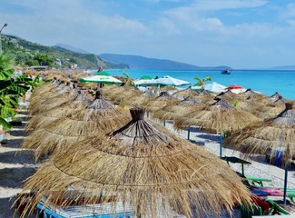 Vista de la Playa de Borsh, Albania, con casetas, tumbonas y parasoles, sin gente, frente al agua turquesa del Adriático.