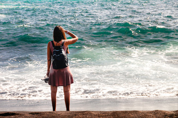 Rear view of a brunette girl looking at ocean. Freedom concept, holiday, beach